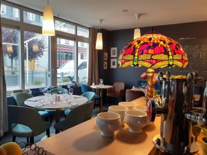 un ristorante con tavoli e sedie e un lampadario a braccio in vetro colorato di La Pomme d'Or a La Charité