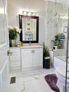 a bathroom with a sink and a toilet and a mirror at Lilen's Home in Toronto