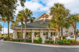 a hotel with palm trees in front of a building at Best Western Plus Wilmington/Carolina Beach in Wilmington