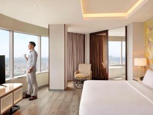 um homem num quarto de hotel com vista em Mercure Jakarta Gatot Subroto em Jacarta