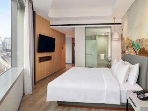 um quarto de hotel com uma cama branca e uma televisão em Mercure Jakarta Gatot Subroto em Jacarta