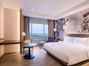 雅加達的住宿－Mercure Jakarta Gatot Subroto，酒店客房配有一张床铺和一张桌子。
