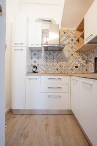 a kitchen with white cabinets and a tile wall at La Finestra su Santa Lucia in Monopoli