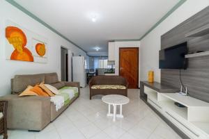 a living room with a couch and a tv at Bay Conceição - Praia da Conceição - 2 dorms, até 7 Pessoas in Bombinhas
