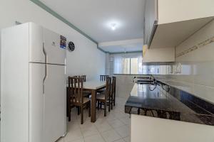 a kitchen with a white refrigerator and a table with chairs at Bay Conceição - Praia da Conceição - 2 dorms, até 7 Pessoas in Bombinhas