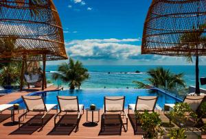 a pool with chairs and the ocean in the background at Pousada Bahia Tambor in Morro de São Paulo