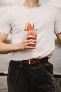 a man in a white shirt holding a drink at RiW Małe Swory - Domek pływający Houseboat in Małe Swornegacie