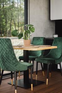 a table with green chairs and a potted plant at RiW Małe Swory - Domek pływający Houseboat in Małe Swornegacie