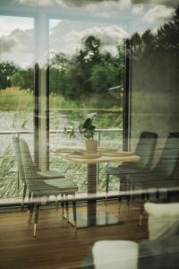 una mesa y sillas frente a una ventana en RiW Małe Swory - Domek pływający Houseboat en Małe Swornigacie