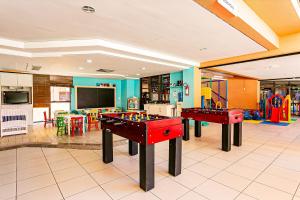 2 mesas de ping pong en una sala con juegos en Resort pé na areia - Studios direto com proprietário JBVJR en Florianópolis