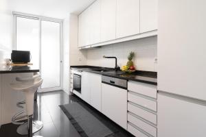 eine weiße Küche mit weißen Schränken und einem Waschbecken in der Unterkunft Stunning Trendy Flat w Balcony - Matosinhos in Matosinhos