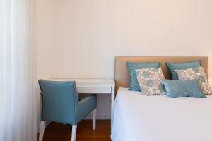 ein Schlafzimmer mit einem Schreibtisch und einem Bett mit einem blauen Stuhl in der Unterkunft Stunning Trendy Flat w Balcony - Matosinhos in Matosinhos