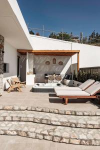 a patio with couches and a table and chairs at Lithos Luxury Villa in Archangelos