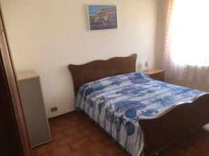 Schlafzimmer mit einem Bett mit einer blauen und weißen Bettdecke in der Unterkunft Appartamento Da Monica in Mirto