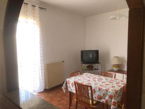 ein Esszimmer mit einem Tisch und einem TV in der Unterkunft Appartamento Da Monica in Mirto