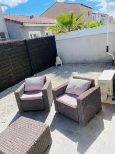 two wicker chairs with pillows sitting on a patio at Jolie maison de village 2 chambres in Ouveillan