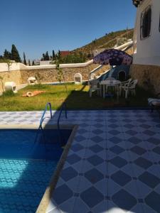 uma piscina com uma mesa e um guarda-sol em Amsa aqua villa em Tétouan