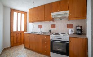 a kitchen with wooden cabinets and a stove and a sink at MinoaHouse 1 bedroom,3 guests,bath tub & patio in Ierápetra +13 photos