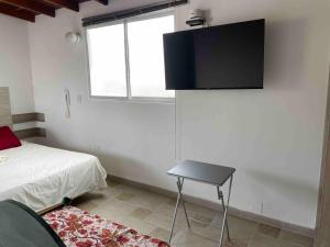 a bedroom with a bed and a television on the wall at Apartamento en San Marcos Envigado con Aire C, Balcón WIFI, Central y dotado in Envigado