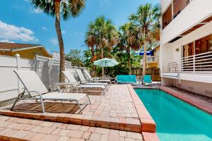 a pool with chairs and an umbrella next to a house at Serene Siesta Key in Siesta Key