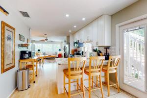 a kitchen with wooden stools and a kitchen with white cabinets at Serene Siesta Key in Siesta Key