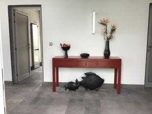 a red table with two black cats under it at Vivenda Moura, Caloura in Caloura