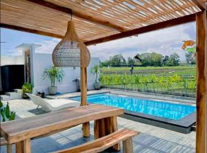 une terrasse avec une table en bois et une piscine dans l'établissement Villa MinSa, à Canggu