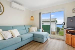 a living room with a blue couch and a tv at Cosy Cabin, Big View ! in Primrose Sands
