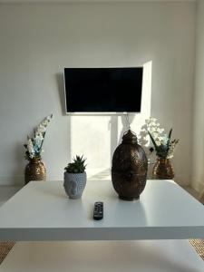uma mesa branca com dois vasos e uma televisão em 3 Bed Cozy Apartment - next to Leeds City Centre & University em Headingley