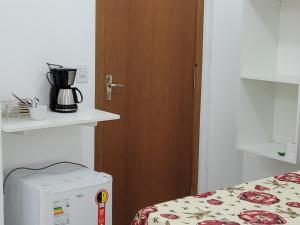a room with a bed and a door and a microwave at Vó Paulina suites in Penha