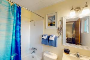 a bathroom with a blue shower curtain and a toilet at Lamplighter Inn - Tropical Fish Cove and Octopus Encounter in Bandon