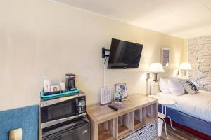 a small hotel room with a bed and a tv at Lamplighter Inn - Tropical Fish Cove and Octopus Encounter in Bandon