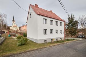 una casa blanca con techo rojo al lado de una calle en LAS I GÓRY Jedlina-Zdrój. Apartament na 5, en Jedlina-Zdrój