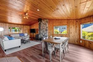 a living room with a wooden ceiling and a table and chairs at Skiou Point Beach House in Tulalip