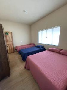 Zimmer mit 3 Betten mit rosa und blauer Bettwäsche in der Unterkunft Rancho do Tomate in São Roque de Minas