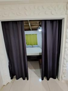 1 dormitorio con cortinas negras y 1 cama pequeña en Baconao apartment 1 room, en Puerto Viejo