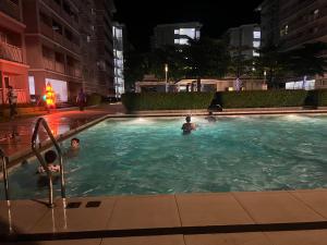 dos personas en una piscina por la noche en Lovers Inn Qc, en Manila