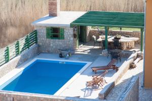 un patio con piscina azul, mesa y sillas en Apartments Belveder, en Pag