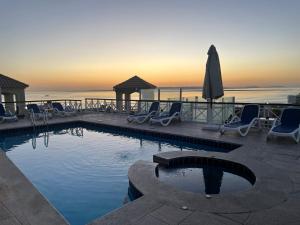 a swimming pool with chairs and an umbrella and the ocean at Suite 69 in Hurghada