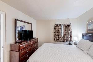 a bedroom with a bed and a dresser with a television at Water's Edge Resort 1002 in Myrtle Beach