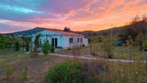 a small white house in a field with a sunset at Alegria rustica in Envendos