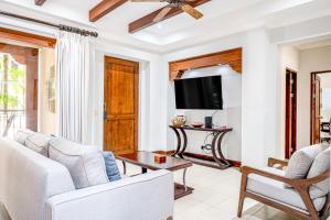 een woonkamer met witte meubels en een flatscreen-tv bij Macaw Oceans Club #2 in Jacó