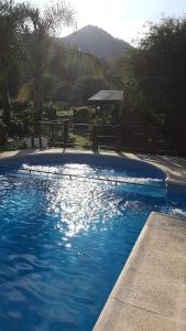 niebieski basen z ławką i palmami w obiekcie Cabañas Ranger w mieście Santa Rosa de Calamuchita