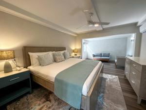 a bedroom with a bed and a dresser and a chair at Blue Haven Holiday Apartments in Christ Church
