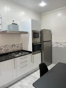 une cuisine avec des armoires blanches et des appareils en acier inoxydable dans l'établissement Appartement du Sacré cœur, à Alger