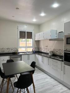 - une cuisine avec des placards blancs, une table et des chaises dans l'établissement Appartement du Sacré cœur, à Alger