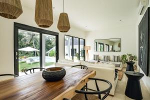 uma sala de estar em plano aberto com uma mesa de madeira e cadeiras em Villa Kirana - Blissful Oasis with Pool & Jungle-View Garden em Ubud