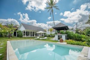 uma piscina em frente a uma casa com uma palmeira em Villa Kirana - Blissful Oasis with Pool & Jungle-View Garden em Ubud