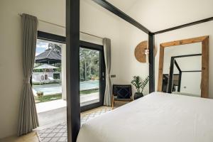 um quarto com uma cama e uma grande janela em Villa Kirana - Blissful Oasis with Pool & Jungle-View Garden em Ubud