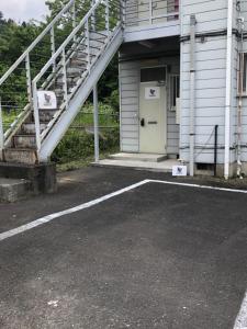 ein Parkplatz vor einem Gebäude mit weißer Tür in der Unterkunft Chichibu Mizuno-stay 水野ステイ最大６名様 in Chichibu